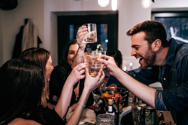 Muž se dvěma ženami a sklenkami alkoholu se baví na firemním večírku