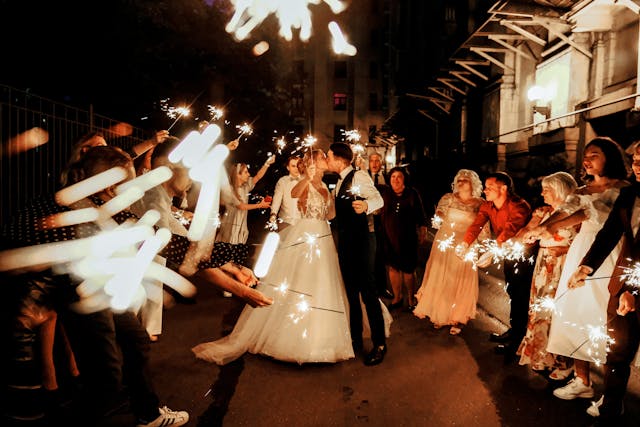 Novomanželé při prvním tanci novomanželů obklopeni svatebními hosty , kteří drží v ruce prskavky