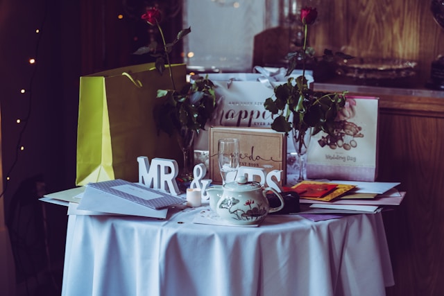 Svatební dary na kulatém stole s bílým ubrusem a svatebními dekoracemi